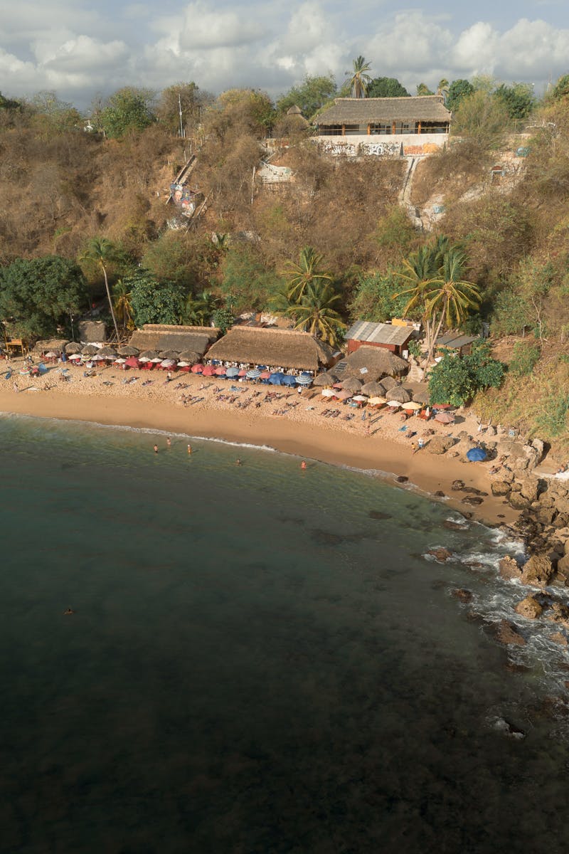 Aerial shot of a beautiful beach with palm trees and umbrellas in Puerto Escondido, Mexico.